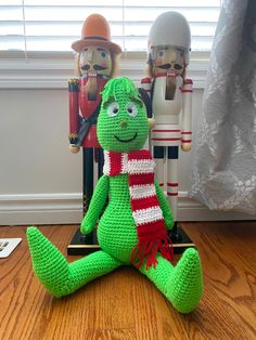 a crocheted stuffed animal sitting on top of a wooden floor next to nutcrackers