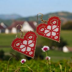 pair of red and white beaded hearts hanging from dangles in front of green grass