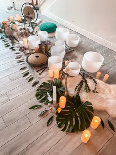 a room filled with lots of candles and plants on top of a wooden floor covered in greenery