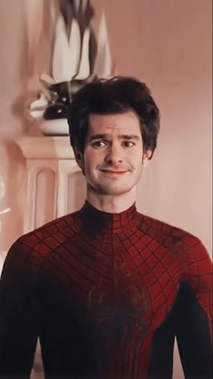 a man in a red and black spider - man suit is smiling at the camera