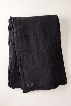 the black towel is folded up on a white surface and has a flower embroidered on it