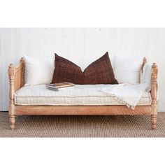 a wooden daybed with two pillows on top of it and a book sitting on the pillow