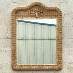 a mirror hanging on the side of a wall next to a brick building with a tree in it