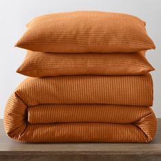 three orange pillows stacked on top of each other