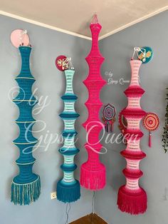 colorful crocheted vases hanging on the wall in a room with blue walls