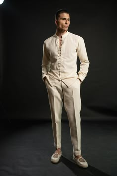 The ivory bandh gala exudes timeless elegance, crafted on silk. Its classic silhouette is adorned with intricate tonal thread embroidery, adding a touch of sophistication and refinement. Paired with a shirt boasting exquisite detailing on its buttons, the ensemble achieves a harmonious balance between tradition and modernity. Completing the ensemble are tailored pants, ensuring a seamless blend of comfort and style. This ensemble embodies understated opulence, perfect for special occasions or fo Elegant White Cotton Silk Sets, White Fitted Cotton Silk Bandhgala, Elegant Off White Straight Pants, Luxury White Pants For Wedding, Elegant Off-white Straight Pants, Designer Cream Kurta For Formal Occasions, Elegant Beige Bandhgala With Resham Embroidery, Elegant Beige Bandhgala With Intricate Embroidery, Elegant Beige Pants For Wedding