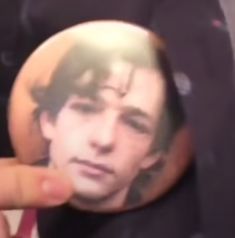 a person holding up a button with the image of a man's face on it