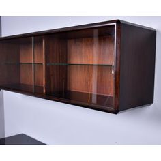 a wooden cabinet with glass shelves on the wall