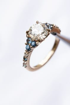 a diamond ring with blue and white stones on it's side, in front of a white background