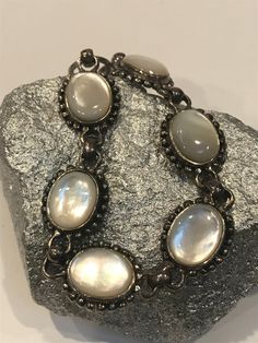 "Thiis is a beautiful, vintage, genuine, handmade Mother of Pearl and sterling silver bracelet that is adjustable and can be worn at either 7 inches or 7 1/2 inches. The bracelet is 5/8\" in width and features 6 Mother of Pearl links that measure about 3/4\" by 5/8\" each. The Mother of Pearls are set in polished sterling silver bezels with sterling silver beading around them. The MOP is so pretty, almost has the look of a Cat's Eye. The bracelet is stamped 925 and weighs about 22.1 grams. Gorge Antique Sterling Silver Adjustable Bracelet For Formal Occasions, Adjustable Antique Sterling Silver Bracelet For Formal Occasions, Adjustable Oval Antique Silver Jewelry, Antique Sterling Silver Adjustable Bracelet, Ornate Adjustable Bracelets For Anniversary, Adjustable Vintage Sterling Silver Bracelet, Adjustable Oval Sterling Silver Bracelet With Oyster Design, Adjustable Oval Sterling Silver Oyster Bracelet, Antique Silver Bracelets For Formal Occasions