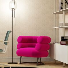 a bright pink chair sits in front of a white desk and bookcase with books on it