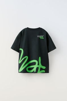 a black t - shirt with neon green graffiti print on the front and back, against a white background