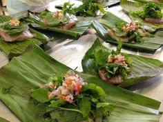 many green leaves with food on them sitting on a table