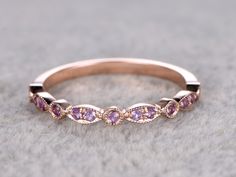 a close up view of a wedding band with pink sapphires on it's sides