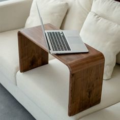 a laptop computer sitting on top of a wooden table in front of a white couch