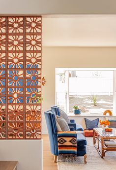 a living room filled with furniture next to a window and wooden paneled divider