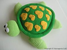 a crocheted turtle with yellow hearts on it's shell is laying down