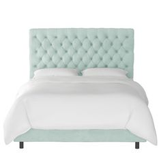 a bed with a light green upholstered headboard and white sheets on it