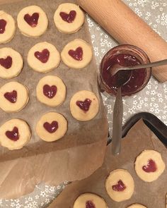 cookies with hearts and jam are on the baking sheet, next to a rolling pin