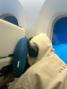 a person sleeping on an airplane seat with headphones attached to the back of it