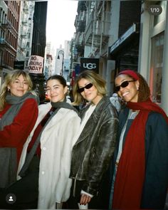 four women are standing in the street posing for a photo