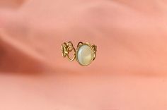 The ring is made from an original ring and a mother-of-pearl stone. The stone is oval and has a dimension of 1cm x 0.8 cm. The ring has a diameter of 1.6mm in diameter. Mother-of-pearl is a stone that produces calm, it has a beneficial effect on emotions and promotes the circulation of energy. It is adjustable to fit all fingers. My jewelry is handmade from materials and fine stones carefully selected in my workshop in Paris. Each stone is natural and unique and may therefore have color variatio Elegant Oval Mother Of Pearl Ring, Elegant Mother Of Pearl Ring As Gift, Elegant Mother Of Pearl Ring For Gift, White Pearl Open Ring In Metal, Bohemian Oval Metal Rings, Vintage Pearl Ring With Gemstone, Gold Cabochon Moonstone Ring, Elegant Brass Rings With Cabochon, Vintage Metal Crystal Ring