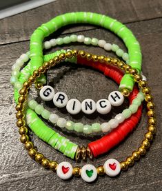 three bracelets with name charms on them sitting on top of a wooden table next to each other