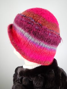 Add some warmth and whimsy to your fall and winter wardrobe with this fun hand knitted boiled and felted 100 percent wool warm winter cloche. This cute wool hat will keep you warm! Dress it up with an oversize shawl or throw it on with a jean jacket. Colors include fuchsia pink, rust and blue with other colorful fun fibers that pop out of the felt for added texture. Embellished with two handmade silk rosettes topped with iridescent vintage glass buttons. Rolled asymmetrical brim for additional i Multicolor Winter Cloche Hat With Short Brim, Multicolor Winter Cloche Hat With Curved Brim, Multicolor Curved Brim Cloche Hat For Winter, Winter Hand Knitted Cloche Hat, Purple Whimsical Winter Hat, Whimsical Purple Winter Hat, Handmade Wool Felt Hat For Winter, Handmade Cloche Hat For Winter, Multicolor Wool Hats