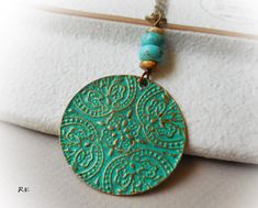 a necklace with a turquoise bead hanging from it's end on a white cloth