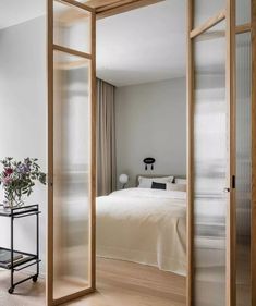 an open door leading to a bedroom with a bed and table in the background,