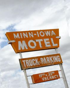 an old neon motel sign in front of a cloudy blue sky with the words'mini - towa motel truck parking'written on it