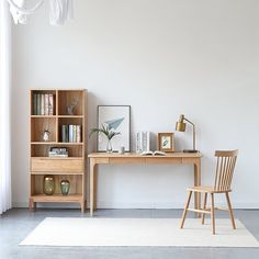 a wooden desk sitting next to a book shelf on top of a white carpeted floor