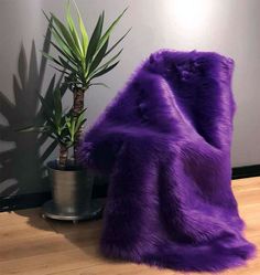 a purple furry chair next to a potted plant