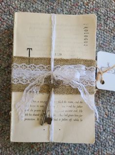 an open book wrapped in twine with a key attached to the front and side