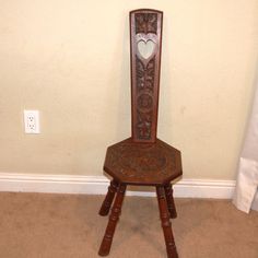 a wooden chair with a heart carved on the back and seat, against a wall