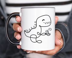 a person holding a coffee mug with a drawing on it