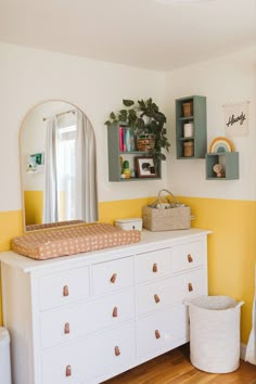 a white dresser sitting in a bedroom next to a mirror