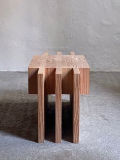 three wooden stools sitting side by side on the floor in front of a white wall