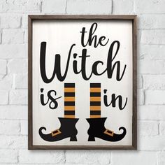 the witch is in sign hanging on a brick wall