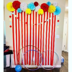 a circus themed backdrop with red, white and blue striped paper pom poms