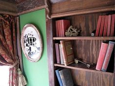 a bookshelf filled with lots of books next to a green wall and window