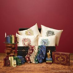 a pile of pillows sitting on top of a wooden table next to books and other items