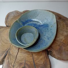 a blue bowl sitting on top of a piece of wood next to a wooden flower