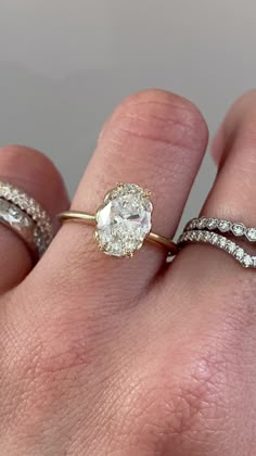 a woman's hand with two rings on it and one has an oval diamond in the middle