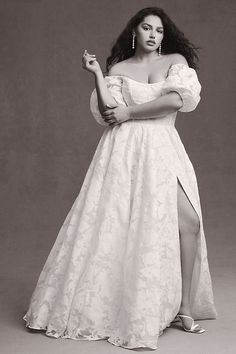 a black and white photo of a woman in a long dress with her arms crossed