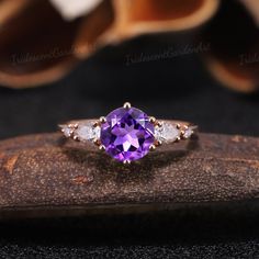 an amethorate and diamond ring sitting on top of a piece of wood