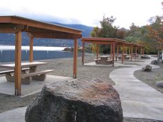 several picnic tables and benches near the water