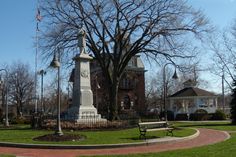 a monument in the middle of a park with benches around it and trees on both sides