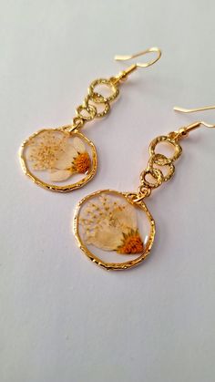 Dangle earrings made with daisy and baby's breath dried flowers in resin encased in brass on gold plated connectors.  Earrings are 2 inches long, lead and nickel free and can be made into clips. Gold Birth Flower Earrings For Gift, Gold Earrings With Birth Flower Design, Gold Resin Earrings, Gold Resin Jewelry With Ear Wire, Gold Flower Jewelry With Pressed Flowers, Gold Round Earrings With Birth Flower, Delicate Gold Birth Flower Earrings, Gold Birth Flower Round Earrings, Gold Earrings With Birth Flower