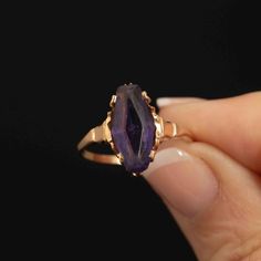 This very pretty handmade 10k gold ring features a striking marquise-shaped purple synthetic glass stone, crafted to resemble an amethyst. The gem, measuring 20mm x 7mm, shows some wear on the surface but remains free of chips, adding character to this unique piece. The design of the ring suggests it may have originally held an Alaskan black diamond, making this replacement with the purple stone a distinctive and creative choice. Crafted with care and attention to detail, this ring is a size 8.2 14k Gold Amethyst Ring Art Deco Style, 14k Gold Art Deco Amethyst Ring, 14k Gold Amethyst Ring In Art Deco Style, Purple Marquise Jewelry For Formal Occasions, Formal Marquise Amethyst Ring, Vintage Marquise Gemstone Jewelry, Fine Jewelry Amethyst Marquise Ring, Fine Jewelry Marquise Amethyst Ring, Marquise Amethyst Ring Fine Jewelry